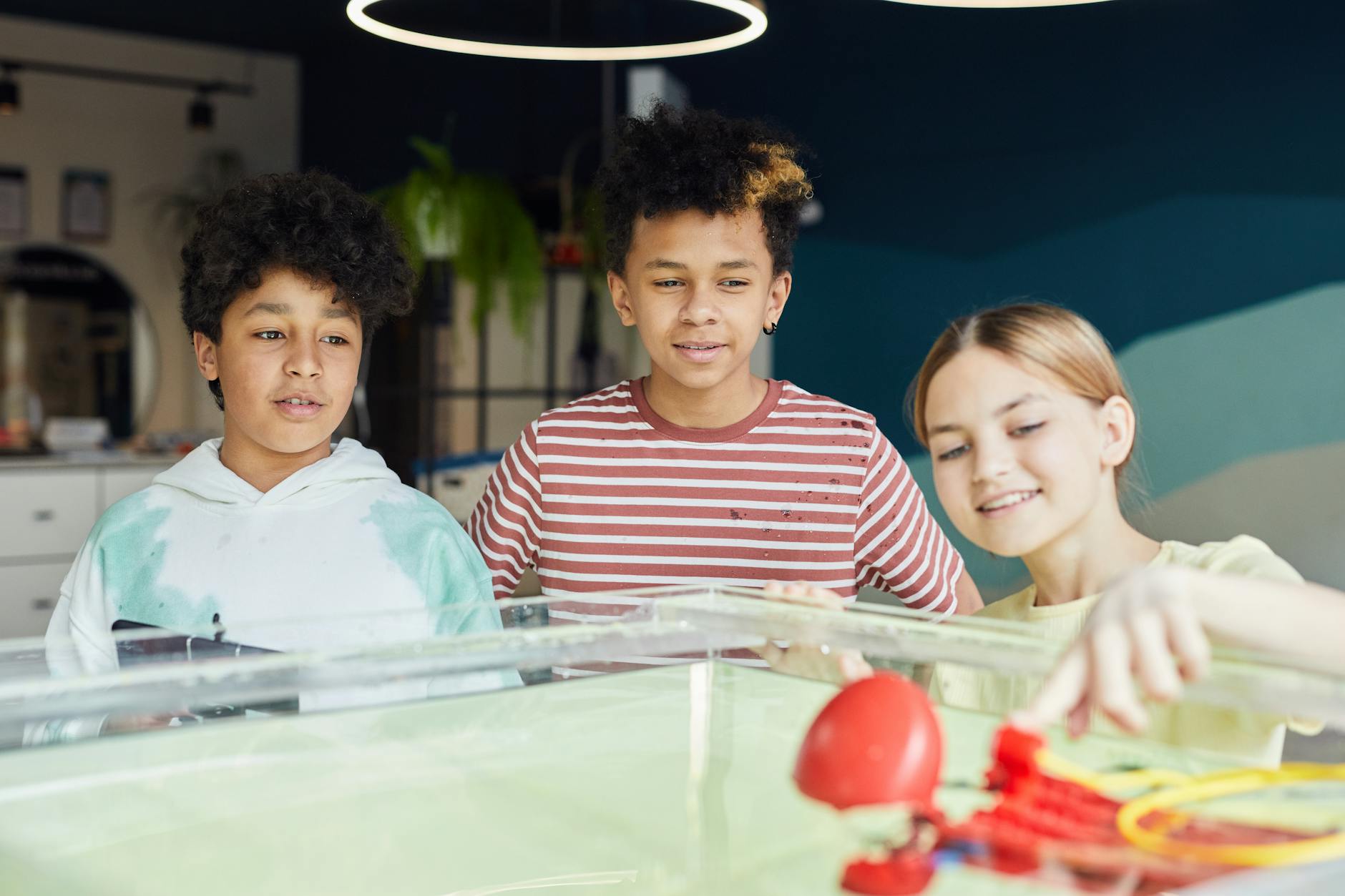 Group of smiling diverse children looking at new flying drone and examining it at workshop