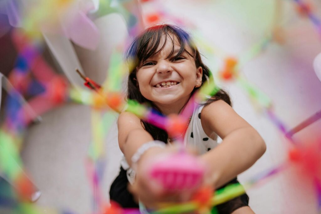 Smiling child engaged with a colorful toy in an indoor setting, conveying happiness and playfulness.