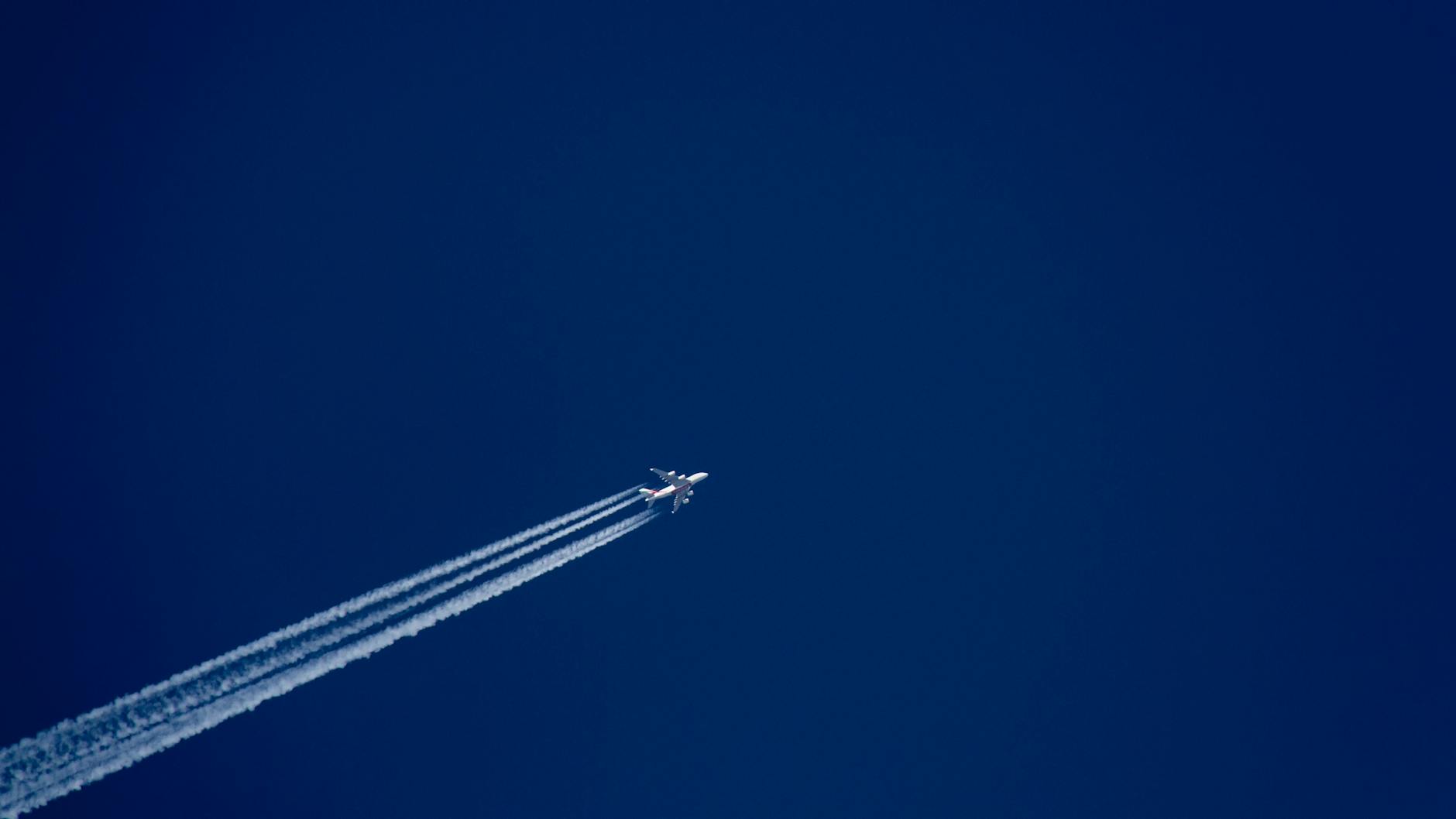 A high-flying airplane leaves distinct contrails against a clear blue sky, capturing the essence of flight.